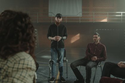 Grupo diverso de pessoas sentadas em círculo durante uma sessão de apoio em saúde mental, em ambiente interno.