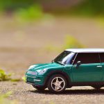 Miniatura verde de um MINI Cooper sobre o pavimento, com fundo externo desfocado.