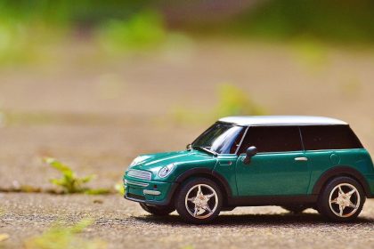 Miniatura verde de um MINI Cooper sobre o pavimento, com fundo externo desfocado.