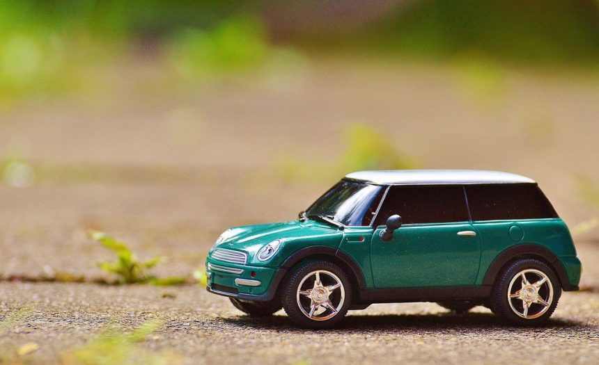 Miniatura verde de um MINI Cooper sobre o pavimento, com fundo externo desfocado.