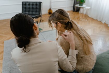 Duas mulheres sentadas juntas em ambiente interno, demonstrando apoio e empatia durante uma conversa.