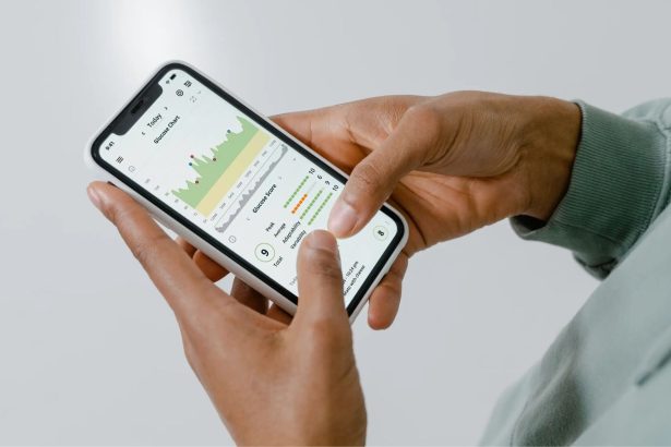 Mãos seguram um smartphone que exibe um aplicativo de acompanhamento de saúde com gráficos e dados.
