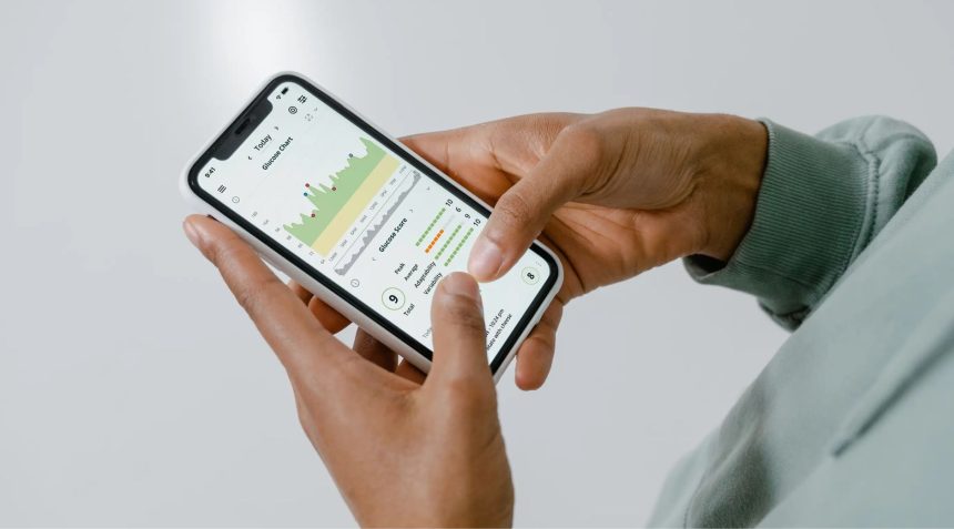 Mãos seguram um smartphone que exibe um aplicativo de acompanhamento de saúde com gráficos e dados.